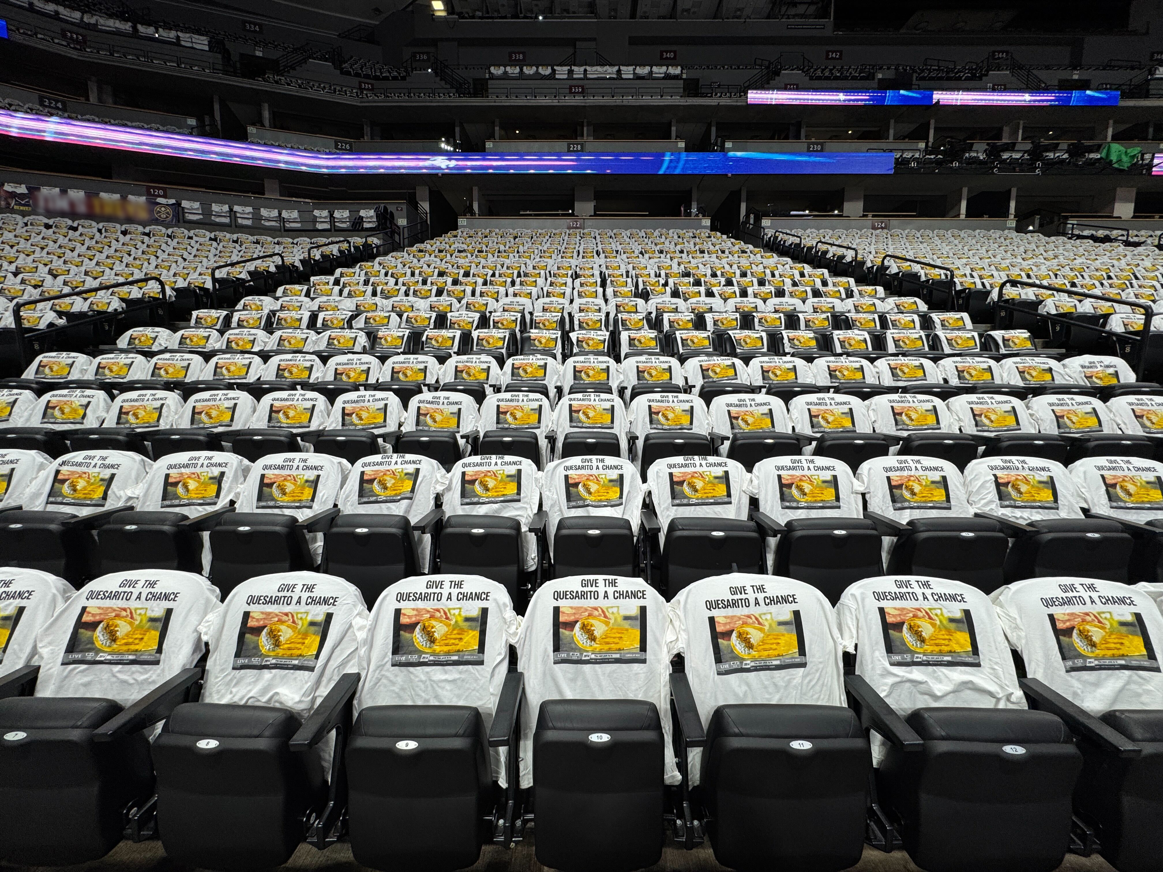 Image of hundreds of stadium seats with shirts draped over them saying "Give the Quesarito a chance" 